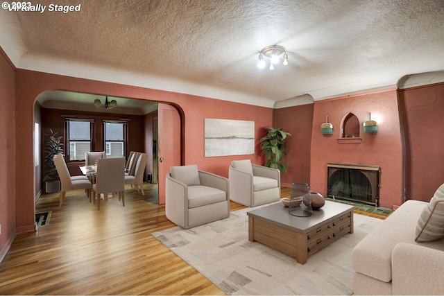 living room featuring a chandelier, a textured ceiling, and light hardwood / wood-style floors