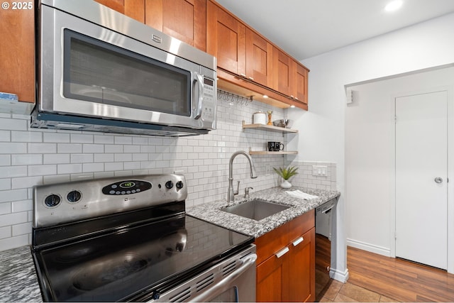 7730 SW Barnes Rd Unit B, Portland, OR 97225 - kitchen with appliances with stainless steel finishes, a sink, brown cabinetry, light stone counters, and backsplash