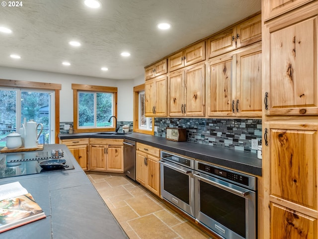 kitchen featuring tasteful backsplash, sink, a textured ceiling, and appliances with stainless steel finishes