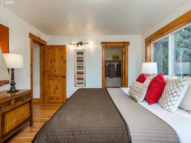 bedroom featuring a walk in closet, light hardwood / wood-style floors, and a closet