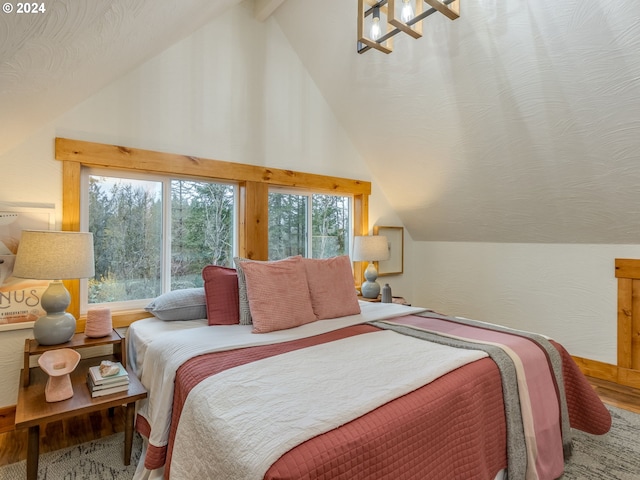 bedroom with a textured ceiling, vaulted ceiling, and wood-type flooring