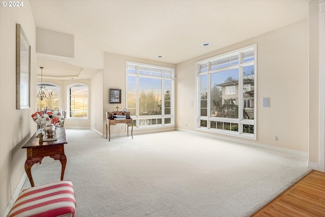 interior space featuring a notable chandelier, a wealth of natural light, and light carpet