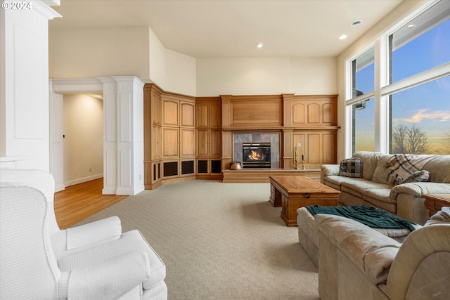 living room featuring light colored carpet, decorative columns, and a towering ceiling