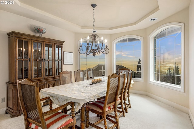 dining space featuring a raised ceiling, a notable chandelier, and light colored carpet