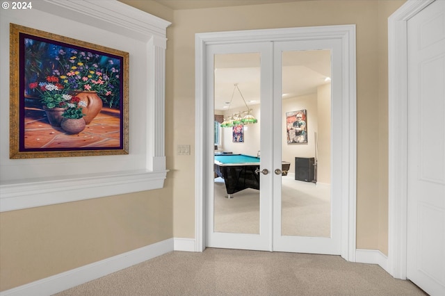 doorway with french doors, light colored carpet, and a chandelier