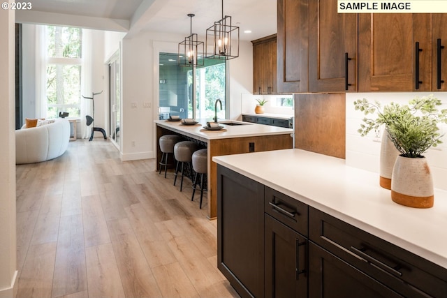 kitchen featuring a chandelier, light hardwood / wood-style flooring, a breakfast bar area, hanging light fixtures, and sink