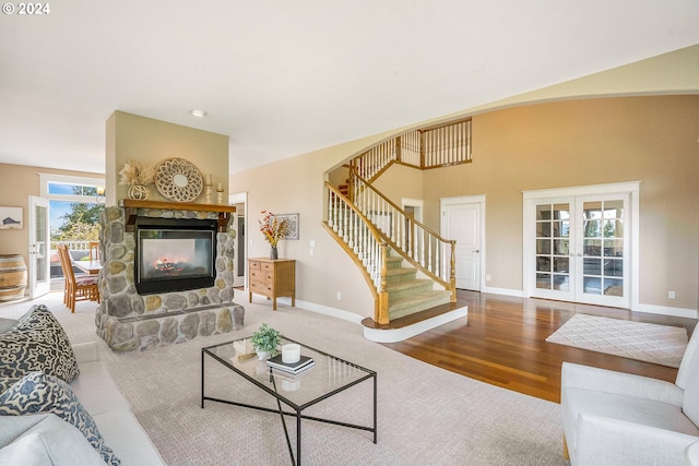 living room with wood-type flooring, a fireplace, plenty of natural light, and french doors