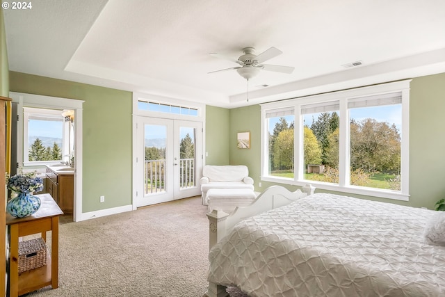 bedroom with a raised ceiling, ceiling fan, access to outside, sink, and light colored carpet