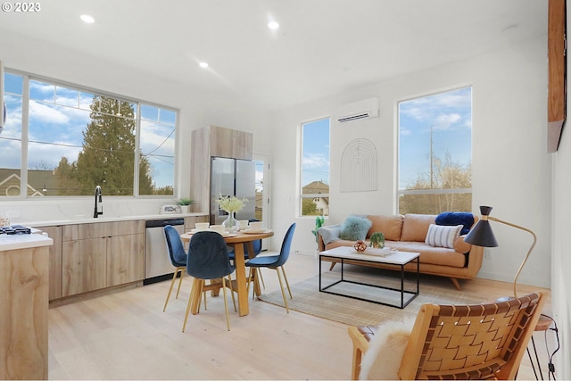 interior space featuring an AC wall unit, sink, light wood-type flooring, and plenty of natural light