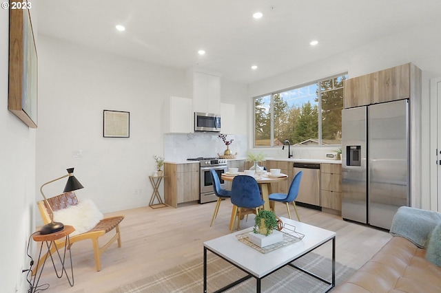 kitchen featuring light hardwood / wood-style floors, tasteful backsplash, stainless steel appliances, and sink