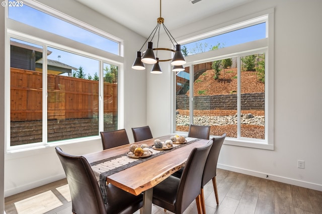 dining space with light wood finished floors, an inviting chandelier, and baseboards