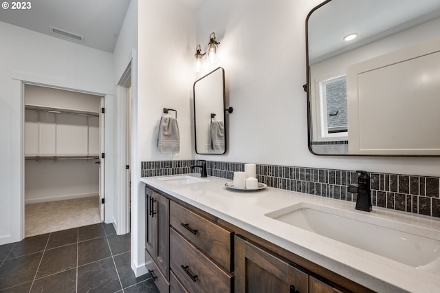 bathroom featuring double vanity, a sink, visible vents, and a walk in closet