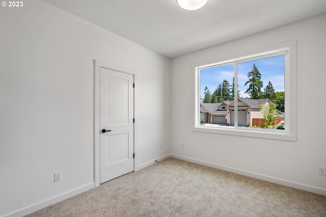 spare room with carpet flooring, a textured ceiling, and baseboards