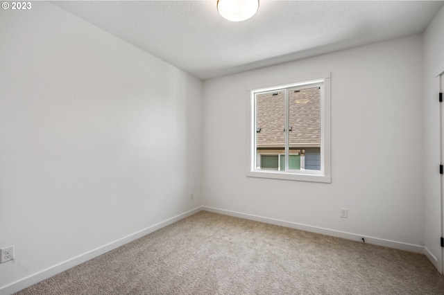 carpeted spare room featuring a textured ceiling and baseboards