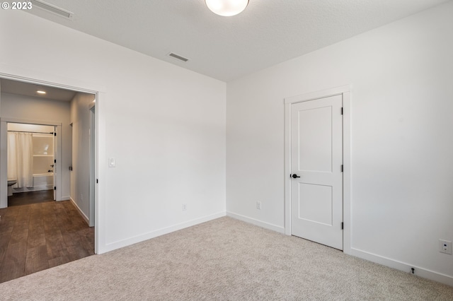 carpeted empty room with visible vents, a textured ceiling, and baseboards