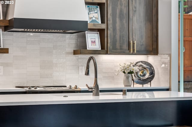 kitchen featuring tasteful backsplash, custom exhaust hood, open shelves, and dark brown cabinets