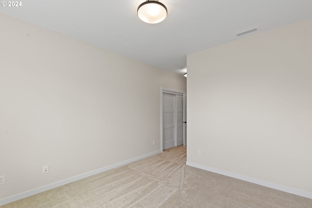 unfurnished room with baseboards, visible vents, and light colored carpet