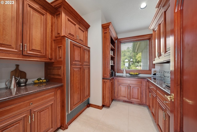 kitchen featuring light tile floors and dark stone counters