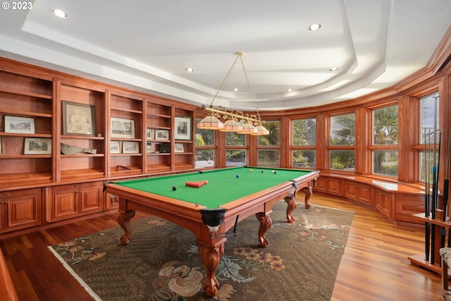 playroom featuring pool table, a tray ceiling, and light wood-type flooring