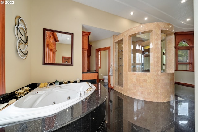 bathroom with tile floors, decorative columns, and tiled bath