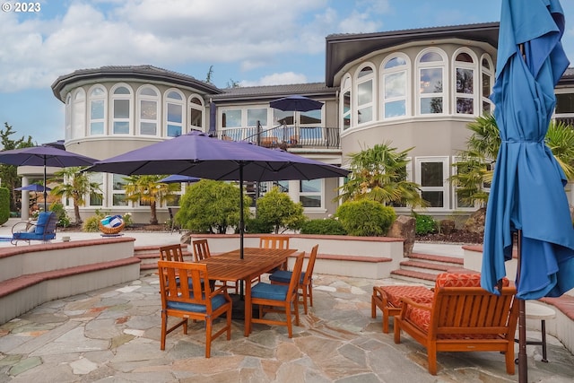 rear view of property featuring a balcony and a patio area