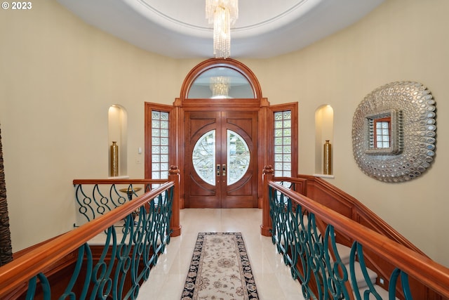 tiled foyer featuring plenty of natural light, a high ceiling, french doors, and an inviting chandelier