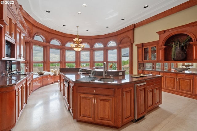 kitchen with a healthy amount of sunlight, sink, an island with sink, a chandelier, and pendant lighting