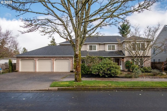 traditional-style house featuring brick siding, driveway, a garage, and fence