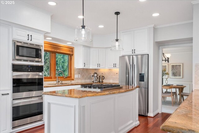 kitchen with stainless steel appliances, light stone countertops, white cabinets, and a sink