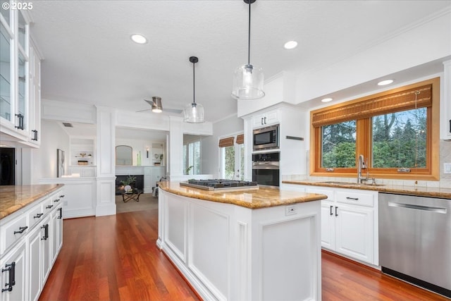 kitchen with a sink, appliances with stainless steel finishes, a kitchen island, and plenty of natural light