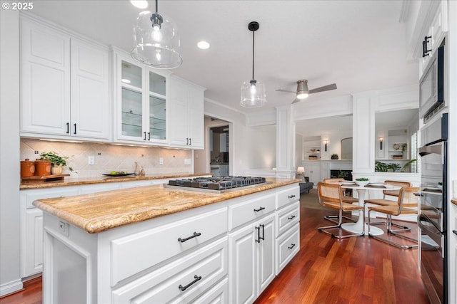 kitchen with dark wood-style floors, ornate columns, stainless steel appliances, decorative backsplash, and white cabinets