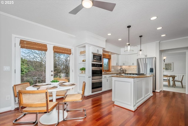 kitchen with stainless steel appliances, decorative backsplash, dark wood-style flooring, and white cabinetry