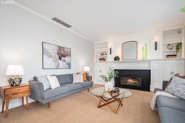 living room with visible vents, a fireplace with flush hearth, built in features, crown molding, and light colored carpet