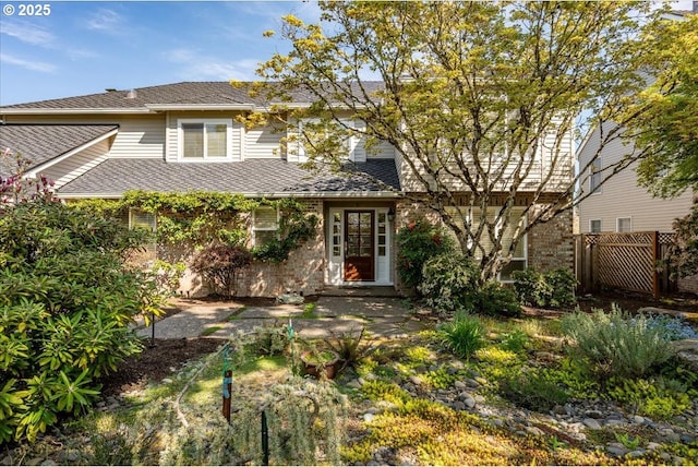 view of front of house featuring fence and a shingled roof