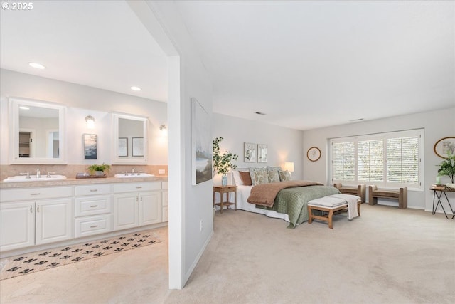 bedroom featuring light colored carpet, ensuite bath, and a sink