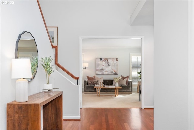 hallway featuring baseboards, stairway, and wood finished floors