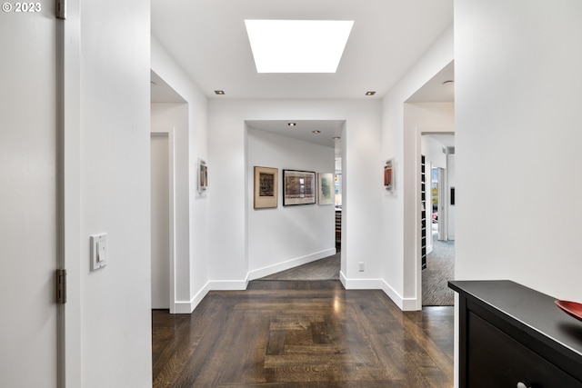 hallway featuring a skylight and dark wood-type flooring