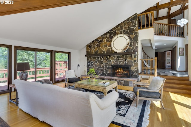 living room featuring a wealth of natural light, a stone fireplace, high vaulted ceiling, and light hardwood / wood-style floors