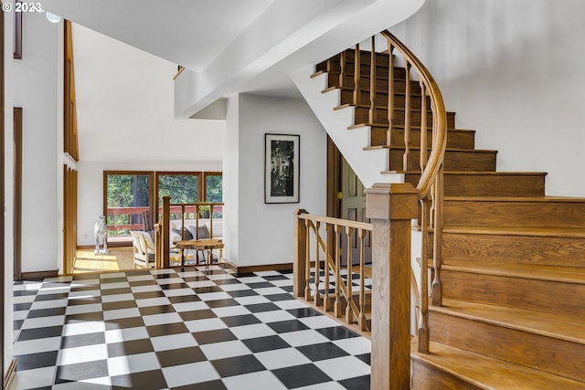 stairway featuring a high ceiling and dark tile floors