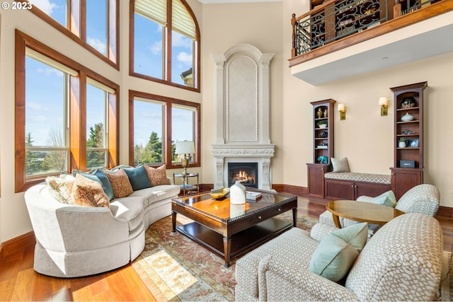 living room featuring hardwood / wood-style floors, a large fireplace, and a towering ceiling