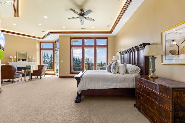 bedroom with a raised ceiling, light carpet, and multiple windows