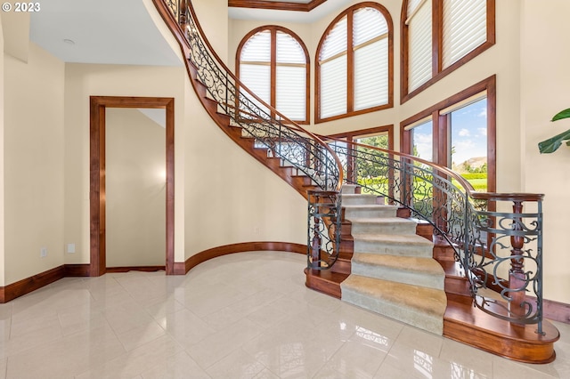 staircase featuring light tile flooring and a high ceiling