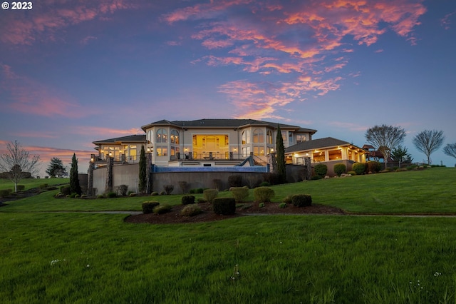 back house at dusk with a lawn