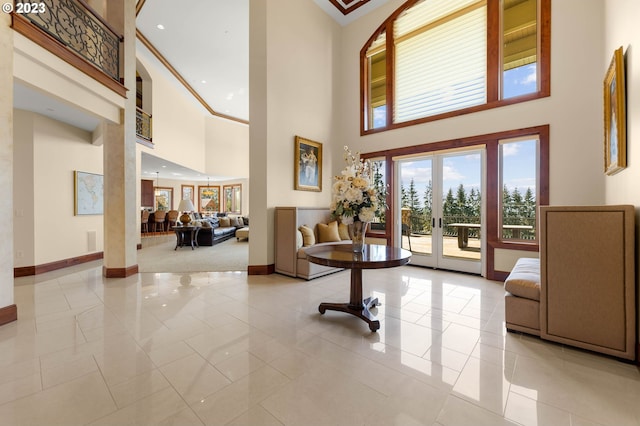 entryway with french doors, crown molding, light tile flooring, and a towering ceiling