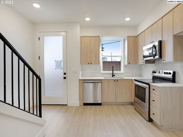 2321 N Lombard St Unit 5, Portland, OR 97217 - kitchen with light brown cabinets, appliances with stainless steel finishes, light wood-style flooring, light countertops, and backsplash