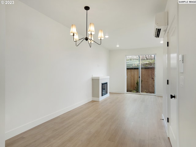 unfurnished living room with a notable chandelier, light wood-type flooring, and an AC wall unit