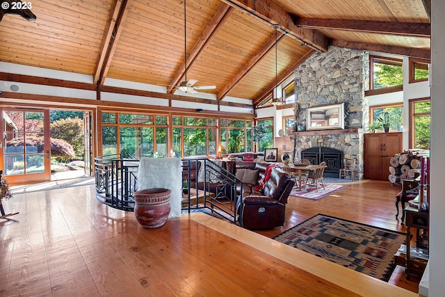 living room with beam ceiling, a stone fireplace, and hardwood / wood-style flooring