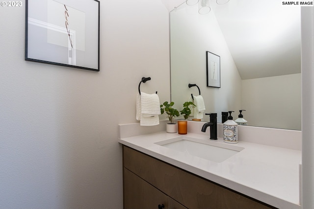 bathroom with lofted ceiling and vanity with extensive cabinet space