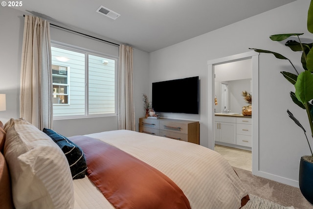 bedroom featuring light colored carpet, sink, and ensuite bath