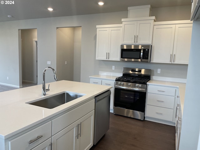 kitchen featuring white cabinetry, an island with sink, appliances with stainless steel finishes, dark wood-type flooring, and sink